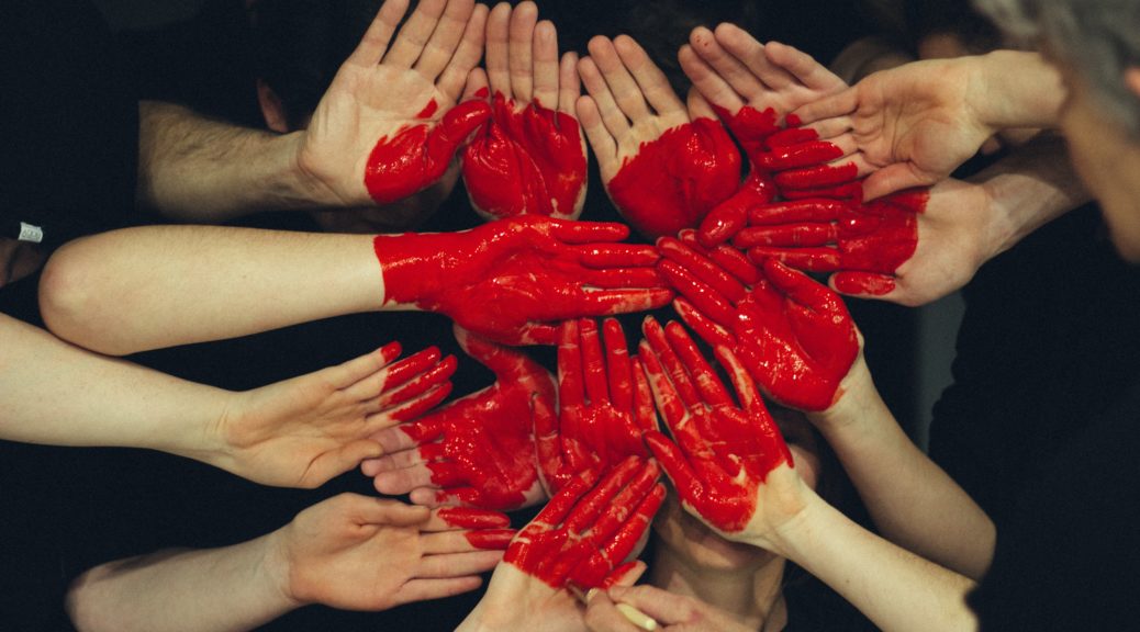 Viele Hände bilden ein rot gemaltes Herz das für Liebe aus dem Team steht